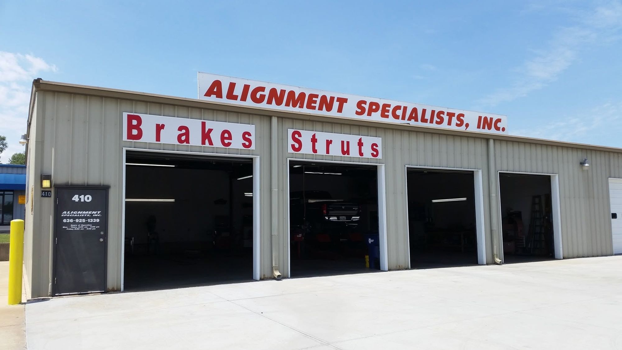 The Alignment Specialists shop in St. Charles: three open bay doors under the red lettered sign, with Brakes and Struts painted over the bays